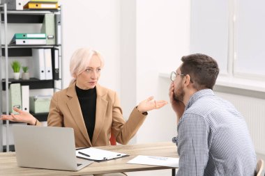 Patron ve stresli çalışan, ofis masasında iş meselelerini tartışıyor.