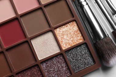 Güzel göz farı paleti ve beyaz masa üzerinde fırçalar, düz yatıyordu.