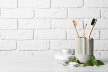 Diş fırçaları, diş ürünleri ve beyaz ahşap masadaki şifalı otlar. Metin için boşluk