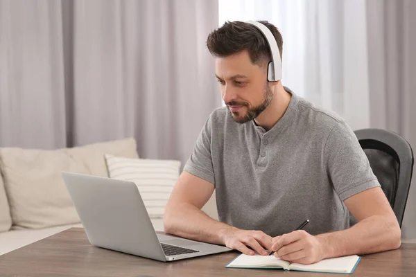 Άντρας Ακουστικά Που Διαβάζει Στο Λάπτοπ Στο Σπίτι Διαδικτυακό Μάθημα — Φωτογραφία Αρχείου