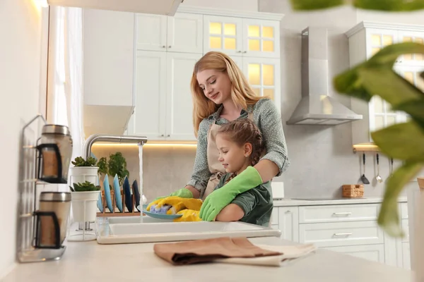 母亲和女儿戴着防护手套 在厨房的洗碗槽上洗盘子 — 图库照片
