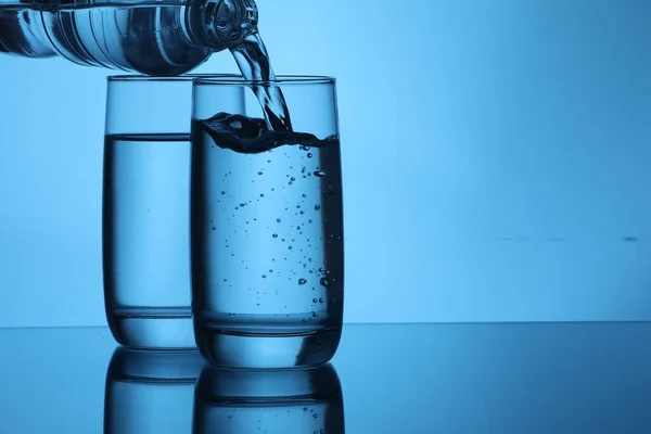 Water Uit Fles Glas Gieten Lichtblauwe Ondergrond Ruimte Voor Tekst — Stockfoto