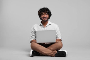 Smiling man with laptop on light grey background
