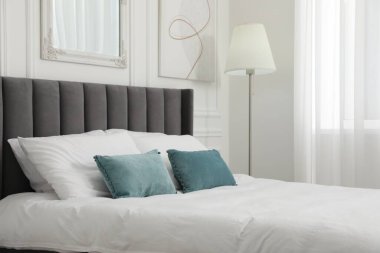 Yatak odasında yastıklar olan büyük, rahat bir yatak. İç tasarım