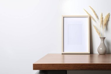 Boş fotoğraf çerçevesi ve vazo. Ahşap masa üzerinde kuru dekoratif çiviler. Tasarım için model