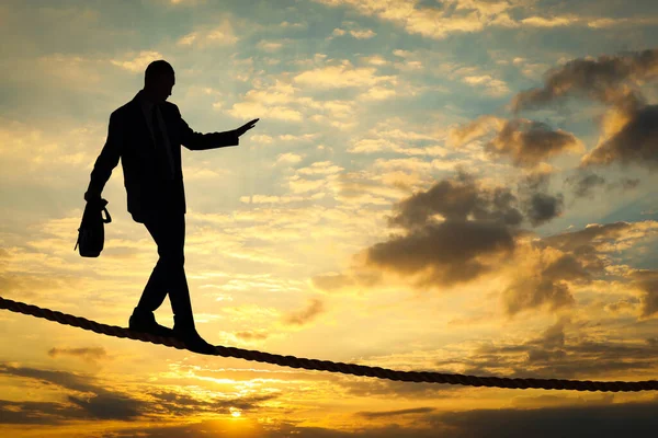 事業のリスクと課題 シルエットの男バランスでロープで日没の空 — ストック写真
