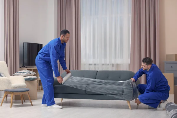 Male Movers Stretch Film Wrapping Sofa New House — Fotografia de Stock