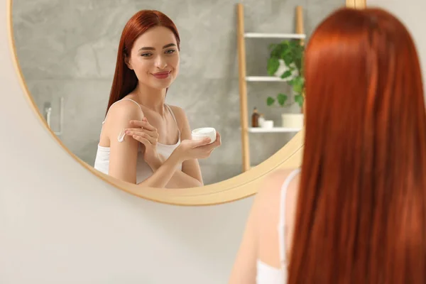 Vacker Ung Kvinna Tillämpa Kroppskräm Axeln Nära Spegeln Inomhus — Stockfoto