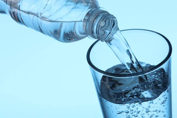 Наливаючи Воду Пляшки Склянку Світло Блакитному Фоні Крупним Планом — стокове фото
