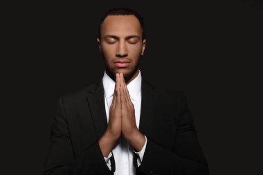 Siyah arka planda elleri sımsıkı bağlı Afrikalı Amerikalı adam Tanrı 'ya dua ediyor.
