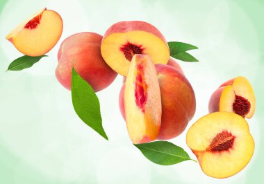 Kesik ve taze şeftali açık yeşil arka planda yapraklarla düşüyor.