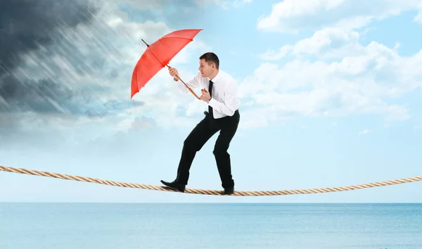 起業家精神のリスクと課題 海の上のロープの上に暴風雨から守る傘を持つビジネスマン — ストック写真