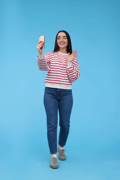 Uśmiechnięta Młoda Kobieta Robi Selfie Smartfonem Jasnoniebieskim Tle — Zdjęcie stockowe