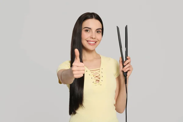 Piękna Szczęśliwa Kobieta Żelaza Włosów Pokazując Kciuki Górę Jasnoszarym Tle — Zdjęcie stockowe