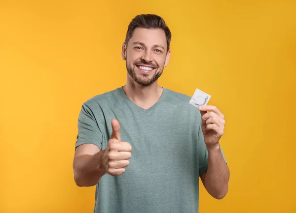 Homem Feliz Com Preservativo Mostrando Polegar Fundo Laranja — Fotografia de Stock