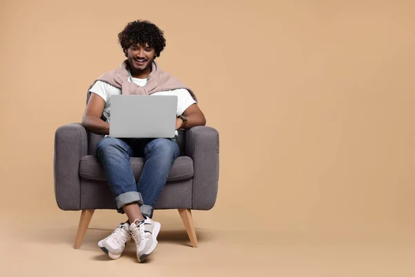 Χαμογελώντας Άνθρωπος Φορητό Υπολογιστή Κάθεται Στην Πολυθρόνα Μπεζ Φόντο Χώρος — Φωτογραφία Αρχείου
