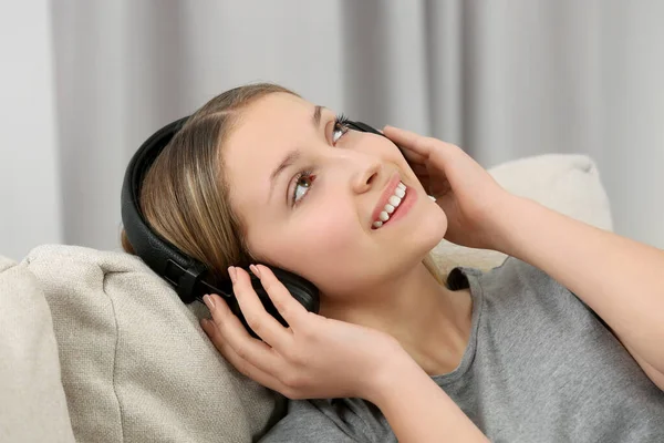十代の女の子は屋内でヘッドフォンで音楽を聴く — ストック写真