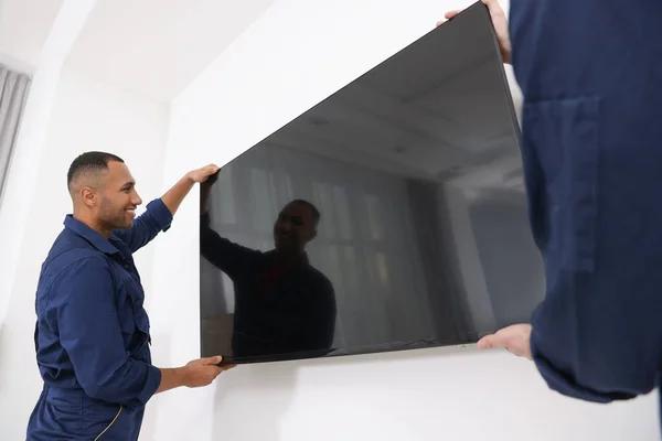 Мужчины Перевозят Плазменный Телевизор Возле Белой Стены Помещении — стоковое фото