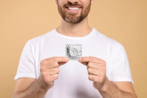 Muž Držící Kondom Béžovém Pozadí Detailní Záběr Bezpečný Sex — Stock fotografie