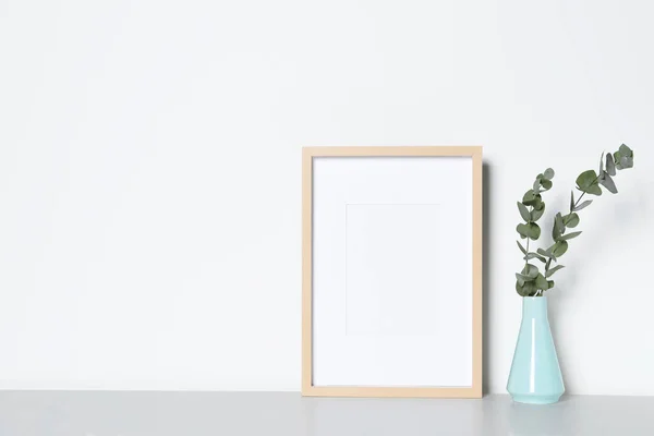Üres Képkeret Váza Dekoratív Eukaliptusz Levelekkel Fehér Asztalon Mockup Tervezéshez — Stock Fotó