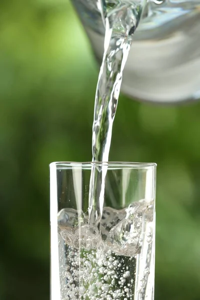 Versare Acqua Dalla Brocca Bicchiere Fondo Verde Sfocato Primo Piano — Foto Stock