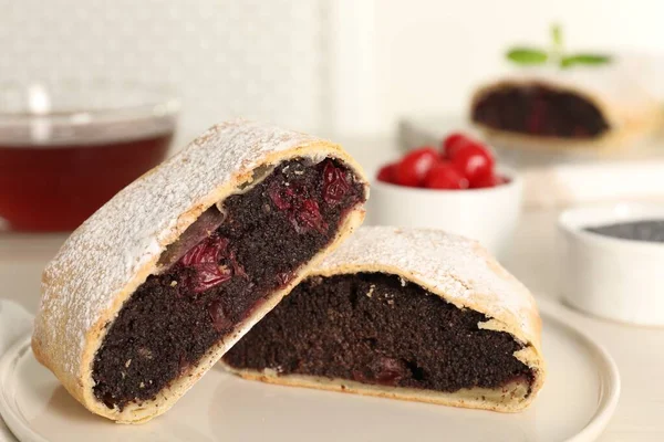 Delicious strudel with cherries and poppy seeds on plate, closeup