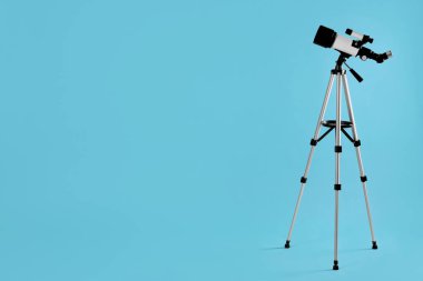 Açık mavi arkaplanda modern teleskopa sahip tripod, metin için boşluk