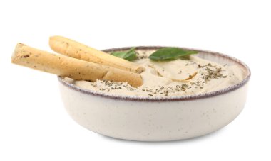 Bir kase lezzetli humus, Grissini çubukları, fesleğen yaprakları ve baharatlar beyaz üzerine izole edilmiş.