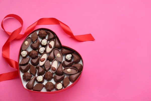 Hartvormige Doos Met Heerlijke Chocolade Snoepjes Lint Roze Ondergrond Plat — Stockfoto