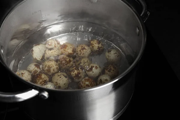 Stock image Cooking quail eggs in pot on electric stove, closeup