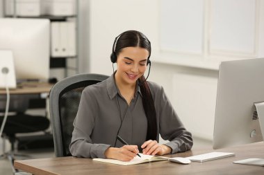 Ofiste çalışan kulaklığı ve defteri olan yardım hattı operatörü