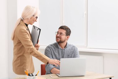 Bilgisayarlı patron ve çalışan ofiste iş meselelerini tartışıyor.