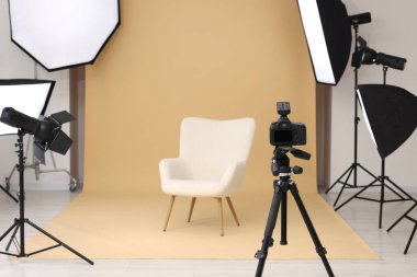 Kamera tripoda, koltuk ve profesyonel ışıklandırma ekipmanları modern fotoğraf stüdyosunda, metin için yer