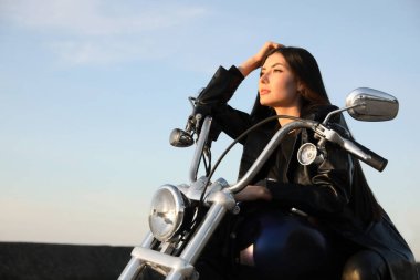 Beautiful young woman sitting on motorcycle outdoors