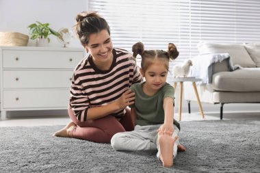 Genç anne ve kızı evde birlikte esniyorlar.