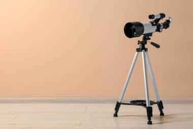 Bej duvarın yanında modern teleskobu olan tripod. Metin için boşluk