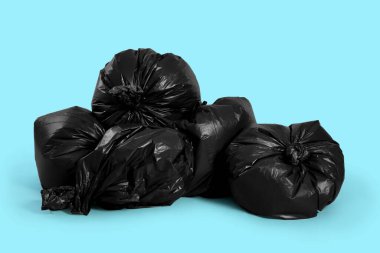 Trash bags full of garbage on light blue background