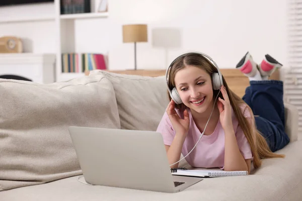 stock image Online learning. Smiling teenage girl in headphones near laptop on sofa at home