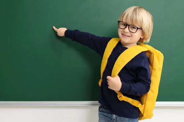 黒板を指してリュックを持つ幸せな小さな学校の子供 テキストのスペース — ストック写真