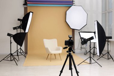 Kamera tripoda, koltuk ve profesyonel ışıklandırma ekipmanları modern fotoğraf stüdyosunda, metin için yer