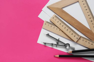Pembe arka planda farklı cetvel, kalem ve pusula var. Metin için boşluk
