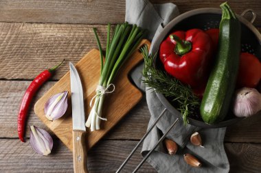 Ratatouille pişiriyorum. Sebzeler, biberiye ve bıçak ahşap masada, düz yatıyordu.