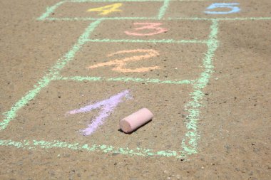 Açık havada asfalt üzerine renkli tebeşirle çizilmiş seksek, yakın plan.