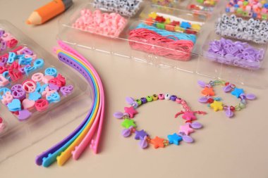 Çocuklar için el yapımı mücevher takımı. Bej arka planda renkli boncuklar, bileklikler ve bileklikler, yakın plan