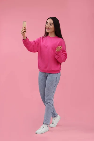 Uśmiechnięta Młoda Kobieta Robi Selfie Smartfonem Różowym Tle — Zdjęcie stockowe