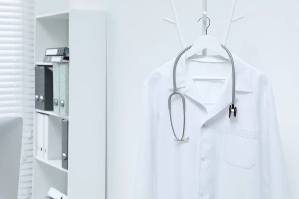 Λευκό Φόρεμα Γιατρού Και Στηθοσκόπιο Κρέμονται Στο Ράφι Στην Κλινική — Φωτογραφία Αρχείου