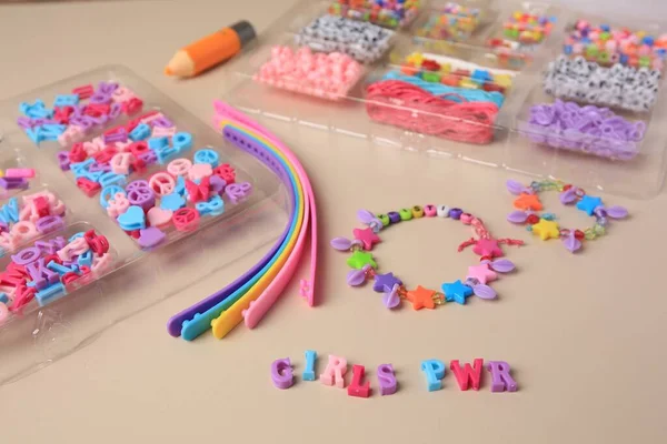 stock image Handmade jewelry kit for kids. Colorful beads, wristbands and bracelets on beige background, closeup