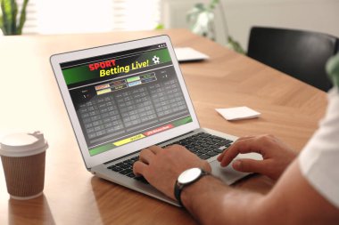 Masada dizüstü bilgisayarla spor bahisleri oynayan adam, yakın plan. Bahisçinin web sitesi ekranda