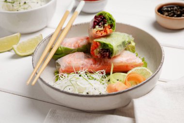 Beyaz ahşap masada servis edilen pirinç kağıdına sarılı nefis börekler, yakın plan.