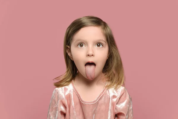 Lustiges Kleines Mädchen Zeigt Ihre Zunge Auf Rosa Hintergrund — Stockfoto